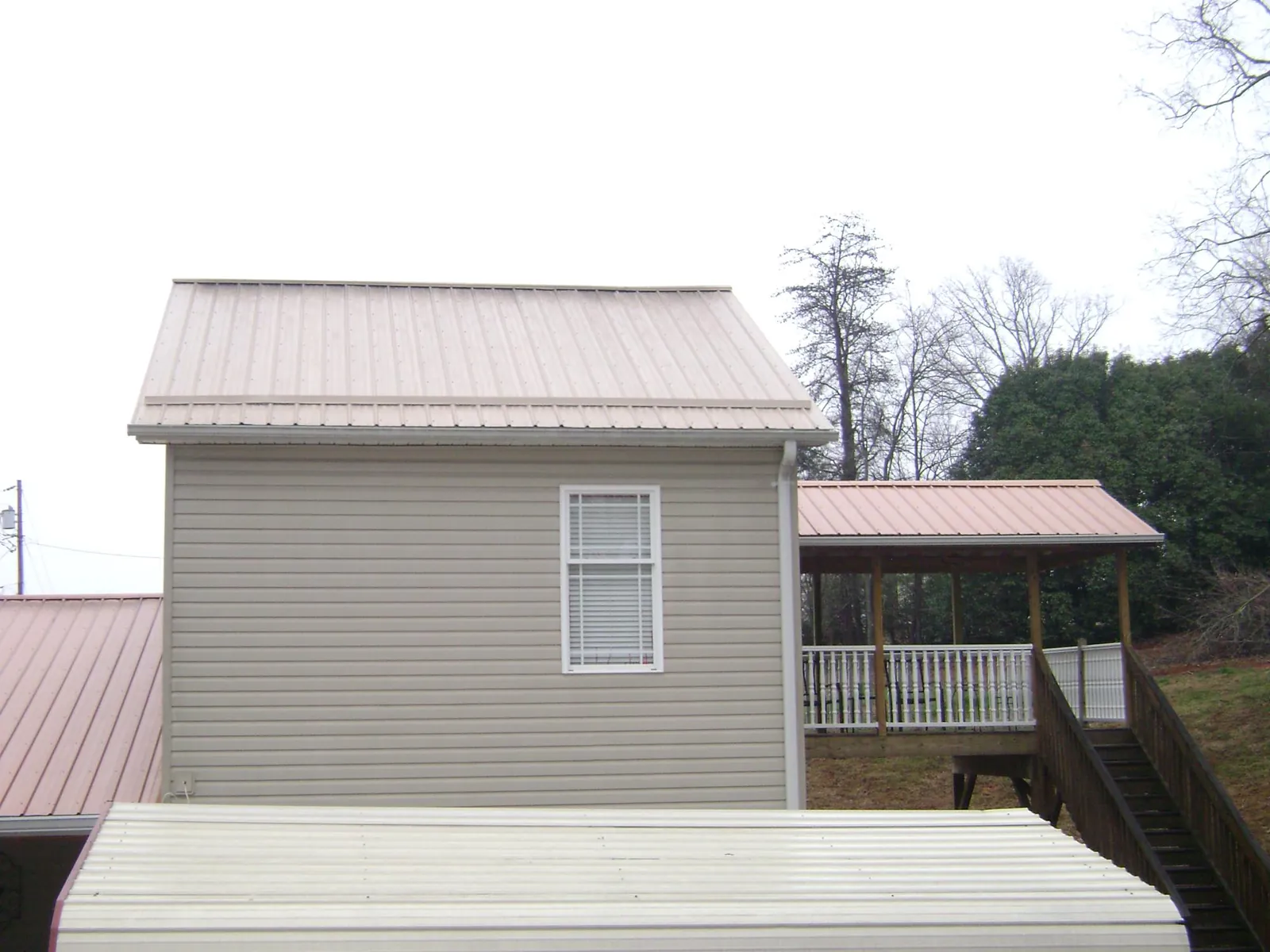 Tan metal roofs on a two story addition and attached porch, from a Roof Replacement job in Middleburg