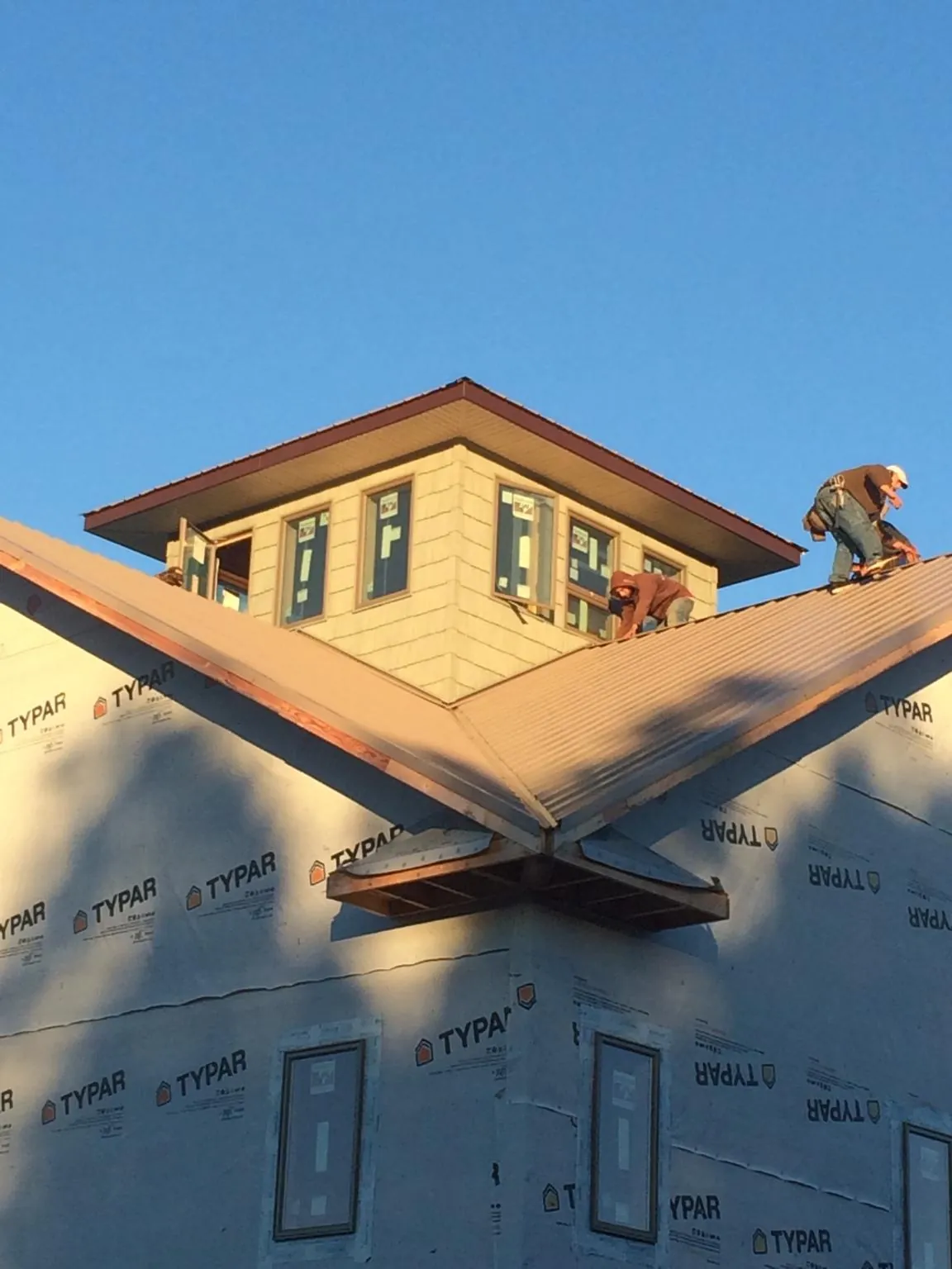 Roofers working around a rooftop cupola on a new metal roof at sunset — Roof Waterproofing in Middleburg by Roofing Brothers